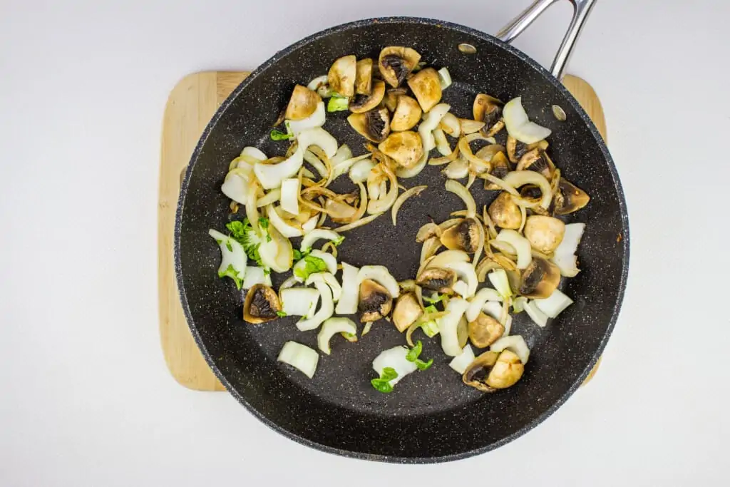sauteeting the onions and mushrooms in a large black skillet