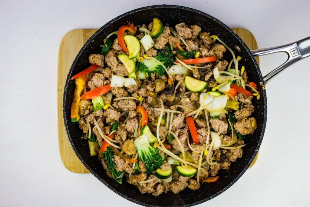 the cooked vegetables and ground pork mixture are in one large skillet