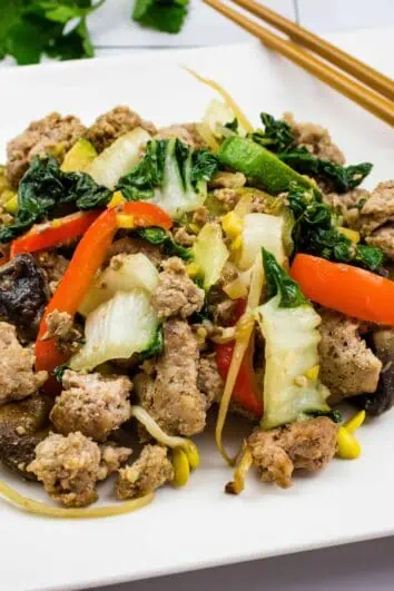 spicy keto pork stir fry on a square plate with chopsticks