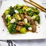 keto beef and broccoli on a square plate with chopsticks