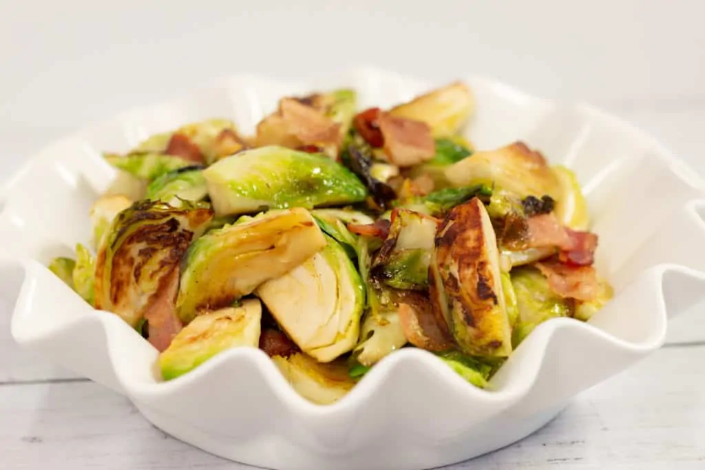 Keto-friendly Brussels sprouts with bacon and maple syrup in a white bowl.