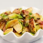 Keto-friendly Brussels sprouts with bacon and maple syrup in a white bowl.