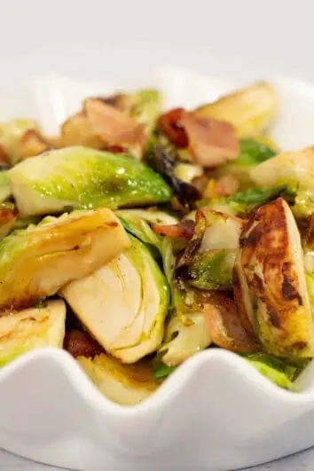 Keto-friendly Brussels sprouts with bacon and maple syrup in a white bowl.