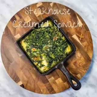 keto steakhouse creamed spinach in a cast iron dish on a wooden board
