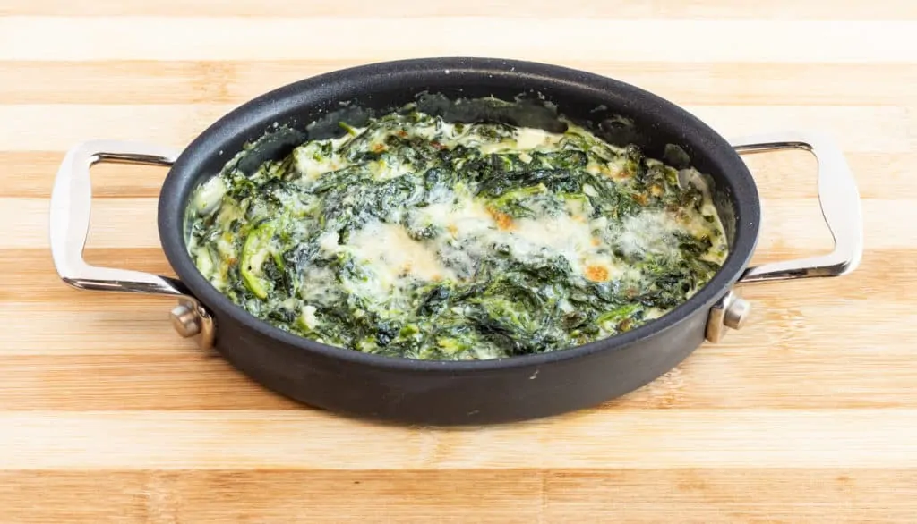 bubbly and cheesy keto friendly creamed spinach in an oval baking dish