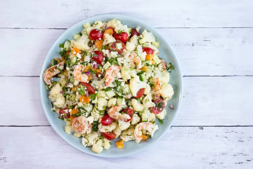 A colorful salad with shrimp, cauliflower and veggies in a lemon dressing
