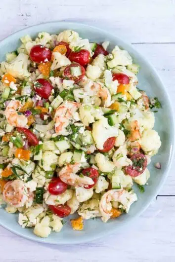 A colorful salad with shrimp, cauliflower and veggies in a lemon dressing
