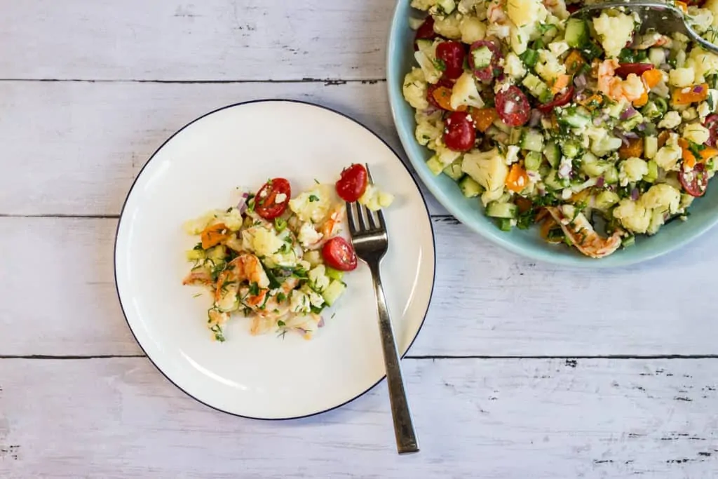 A colorful salad with shrimp, cauliflower and veggies in a lemon dressing