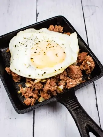 keto corned beef hash on a plate with an egg on top