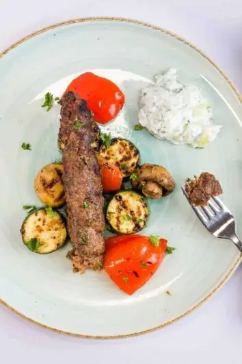 keto low-carb kefta beef kabobs on a plate with tzatziki and grilled veggies