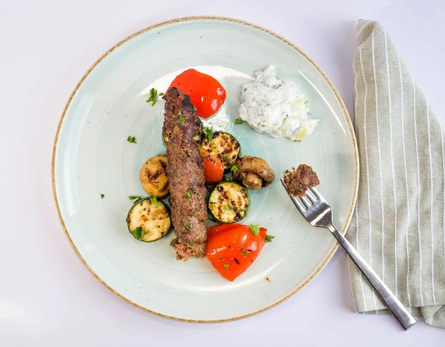 keto low-carb kefta beef kabobs on a plate with tzatziki and grilled veggies