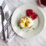 Keto and low-carb sausage and egg cups on a plate with raspberries