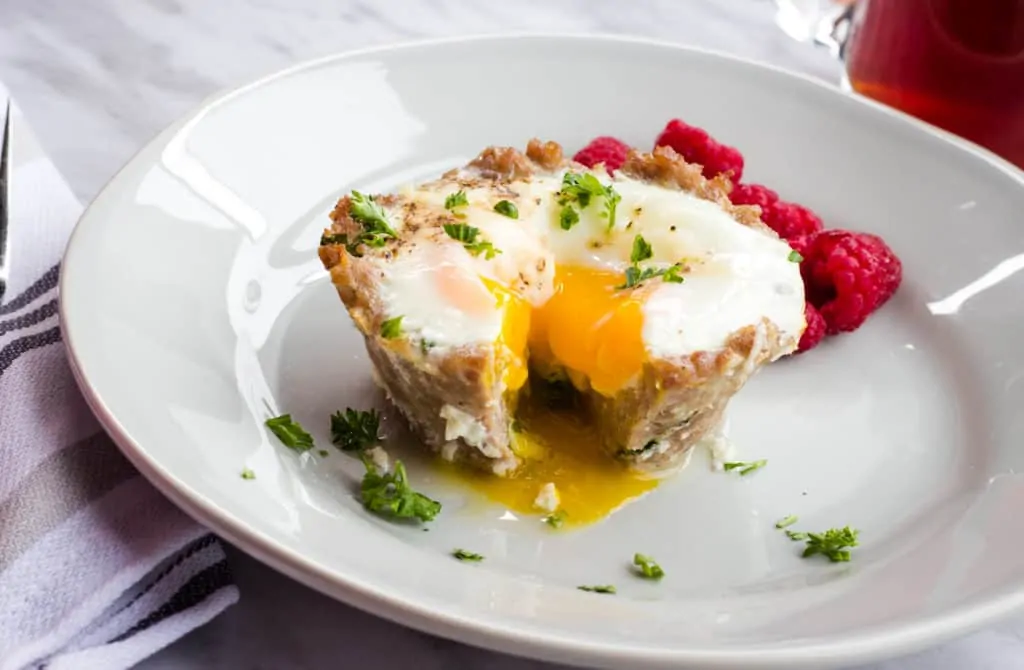 keto sausage 'n egg cups on a plate with raspberries