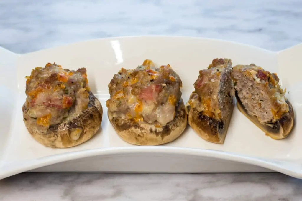 three keto and low carb bacon, sausage and cheese stuffed mushroom caps on a plate