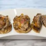 three keto and low carb bacon, sausage and cheese stuffed mushroom caps on a plate