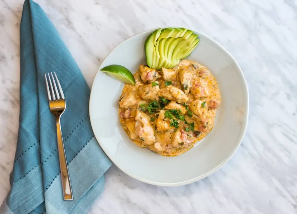 keto and low carb chicken taco casserole on a plate with lime and fanned avocado
