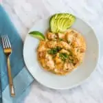 Keto and Low Carb Chicken Taco Casserole on a plate with lime and fanned avocado