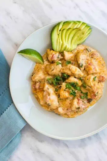 keto and low carb chicken taco casserole on a plate with lime and fanned avocado