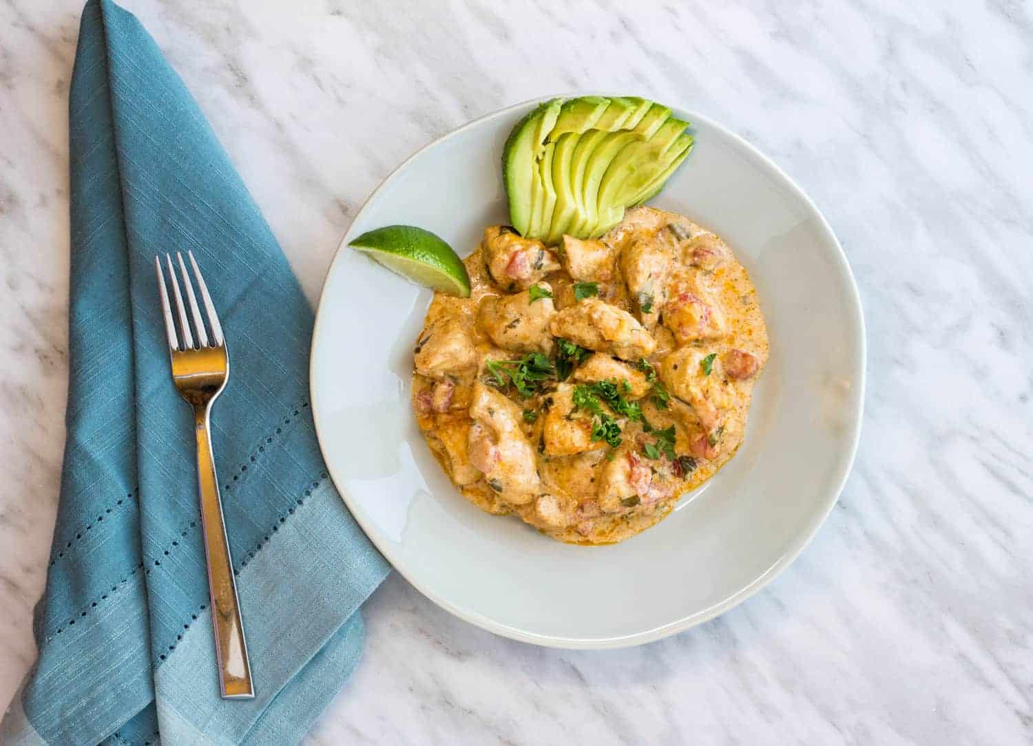 Keto and Low Carb Chicken Taco Casserole on a plate with lime and fanned avocado