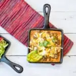 Tex-Mex Beef Casserole in a small square cast iron serving dish with another dish of lettuce and tomato on the side.