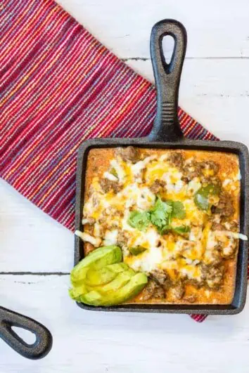 Tex-Mex Beef Casserole in a small square cast iron serving dish with another dish of lettuce and tomato on the side.