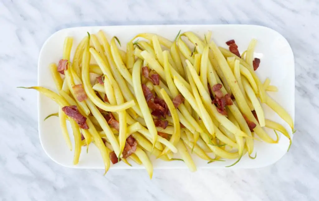 Yellow string beans with bacon on a rectangular plate