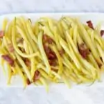 yellow string beans with bacon on a rectangular plate