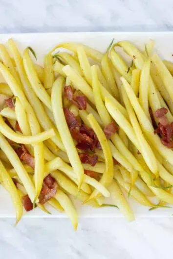 yellow string beans with bacon on a rectangular plate