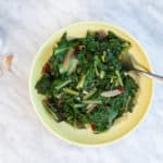 garlicky swiss chard in a yellow serving dish with serving fork