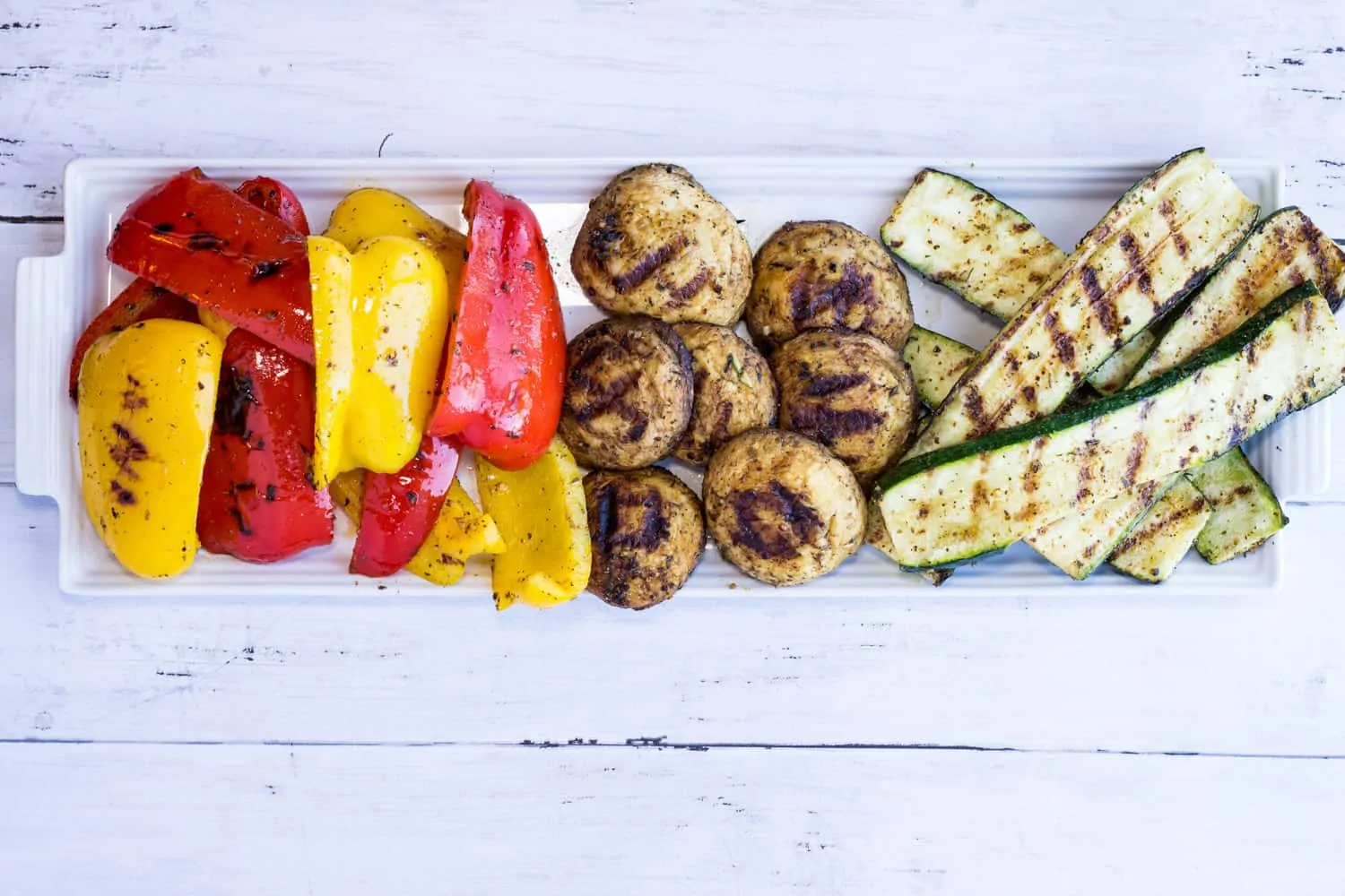 Keto Grilled Veggies with grilled red and yellow peppers, mushrooms, and zucchini on a platter.