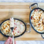 two individual casserole dishes with philly cheesesteak casserole and topped with bubbly cheese