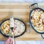 two individual casserole dishes with philly cheesesteak casserole and topped with bubbly cheese