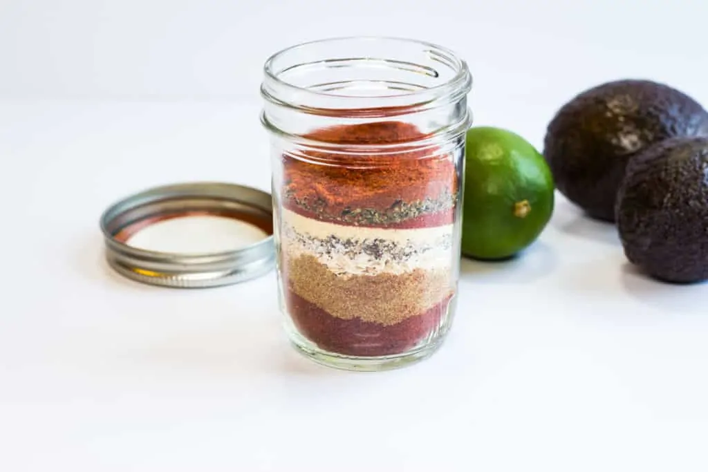 Keto Taco Seasoning in a glass jar with avocado and lime in the background.