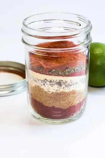 Keto Taco Seasoning in a glass jar with avocado and lime in the background.