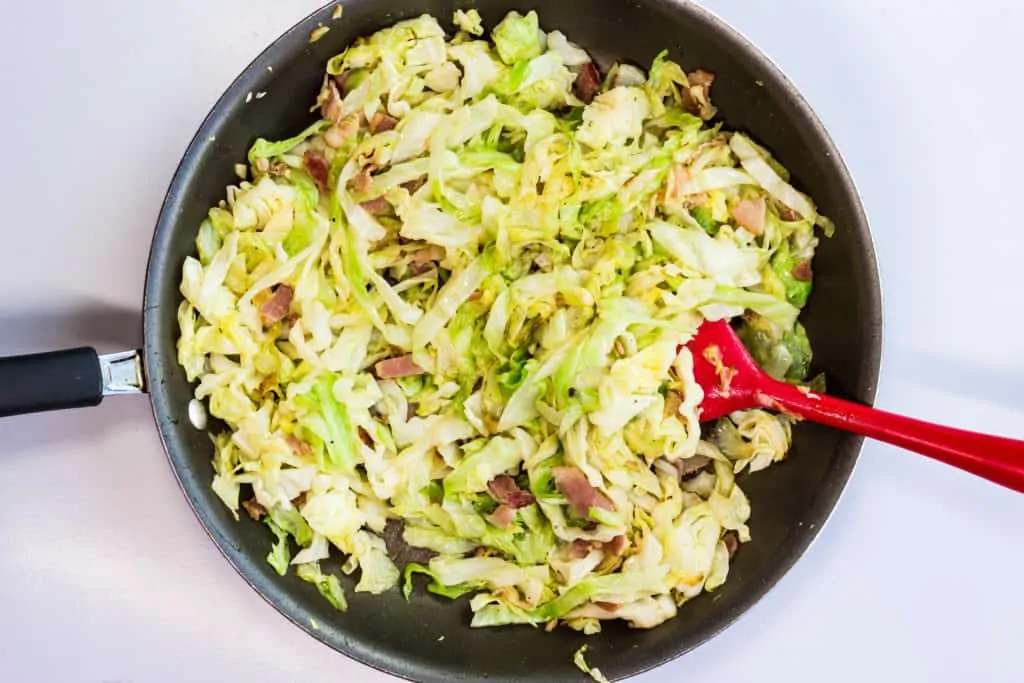 keto sliced cabbage, bacon, and garlic in a skillet.
