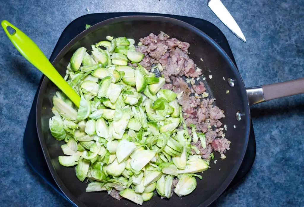 Sliced brussels sprouts and sausage in a pan
