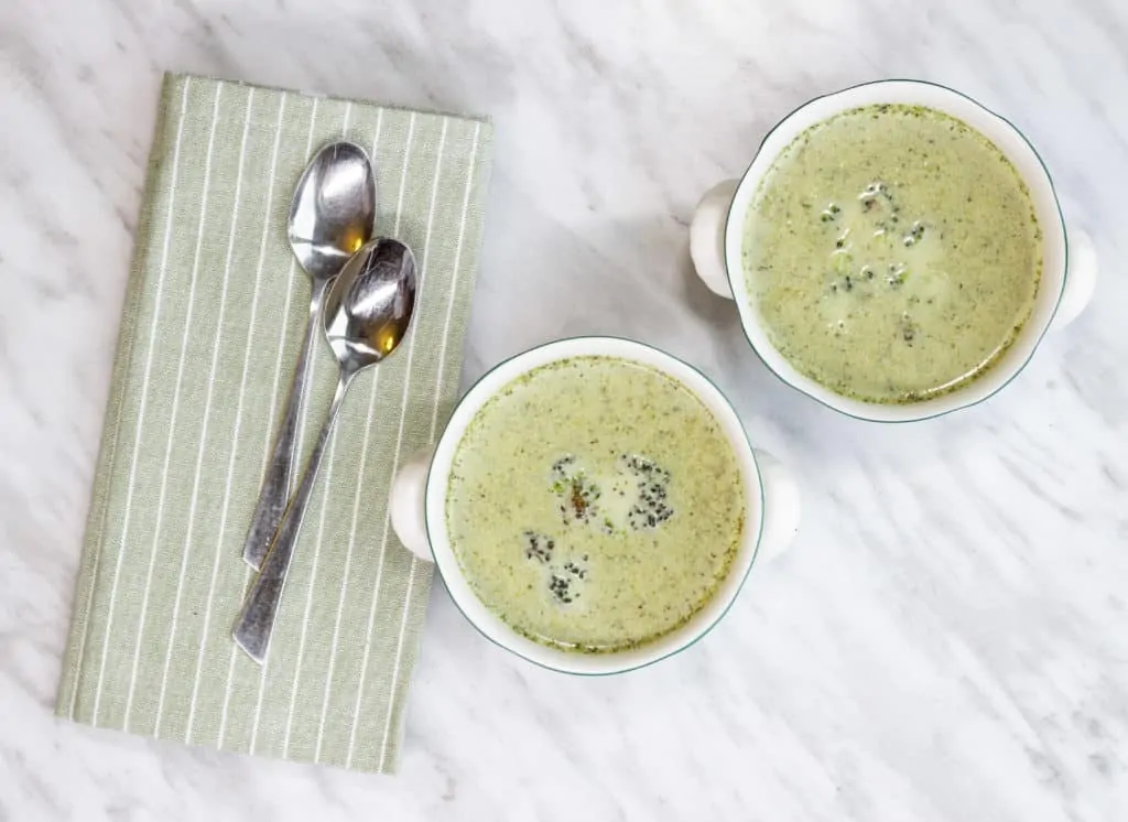 Finished Cream of Roasted Broccoli Soup in two serving bowls with spoons and a napkin.