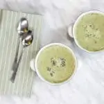 Finished Cream of Roasted Broccoli Soup in two serving bowls with spoons and a napkin.