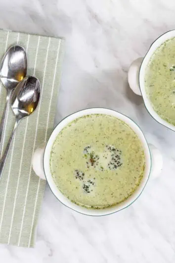 Finished Cream of Roasted Broccoli Soup in two serving bowls with spoons and a napkin.