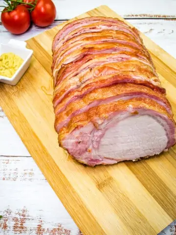 smoked bacon wrapped pork loin on a cutting board