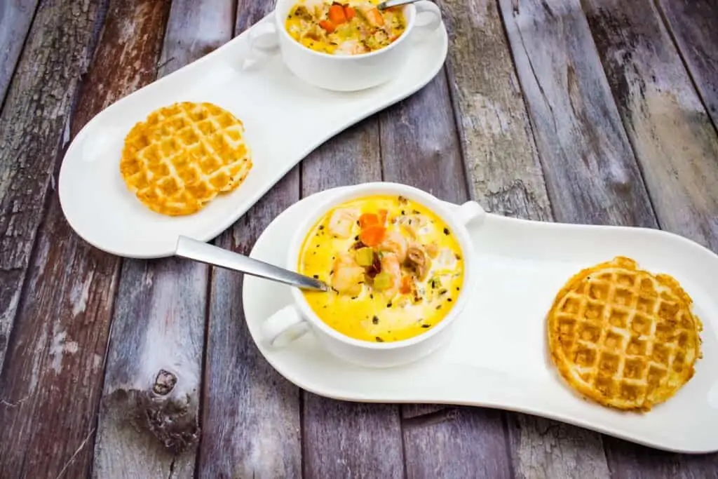 keto shrimp chowder with chipotle on a plate with a chaffle and a second serving in the background