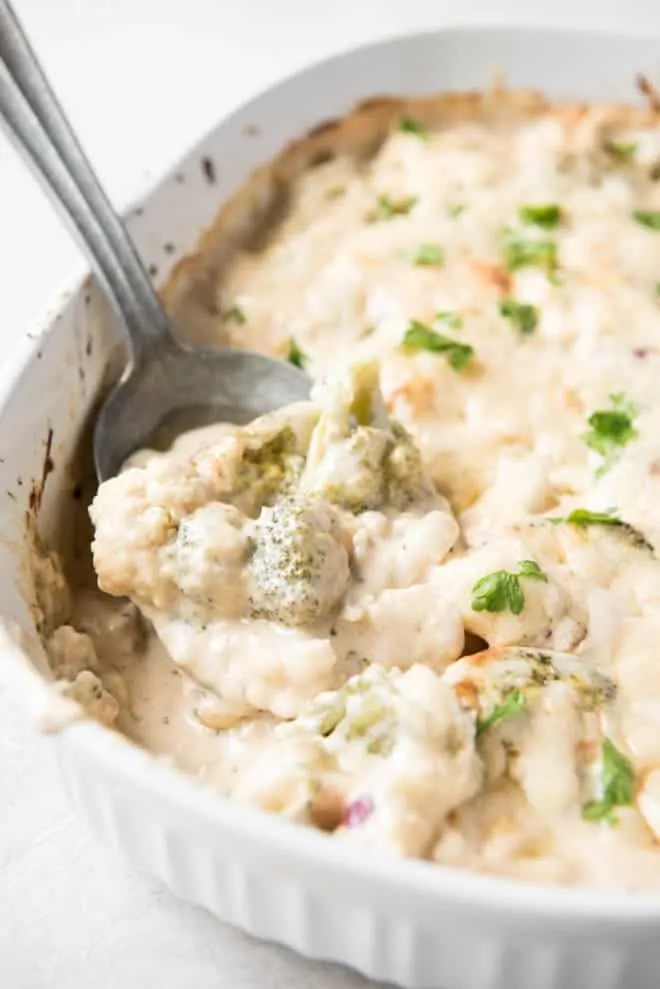 Broccoli Cauliflower Casserole in a white serving dish with a spoon.