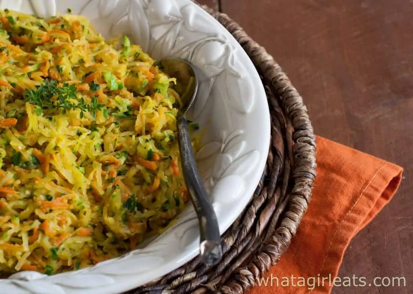 Harvest Squash Casserole in a white serving dish with a spoon atop an orange napkin.