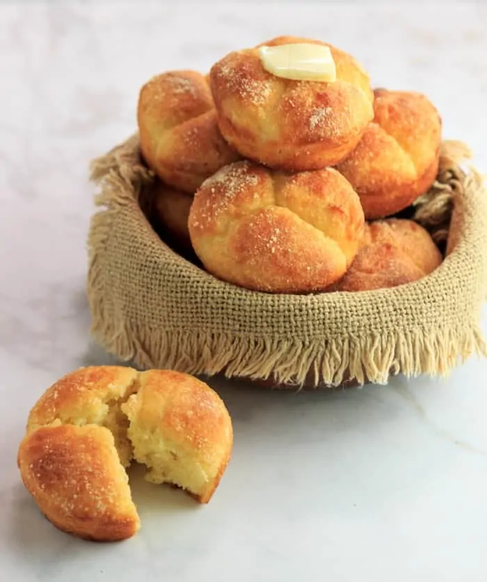 A basket of Pull-Apart Clover Rolls with a pat of butter melting on top.