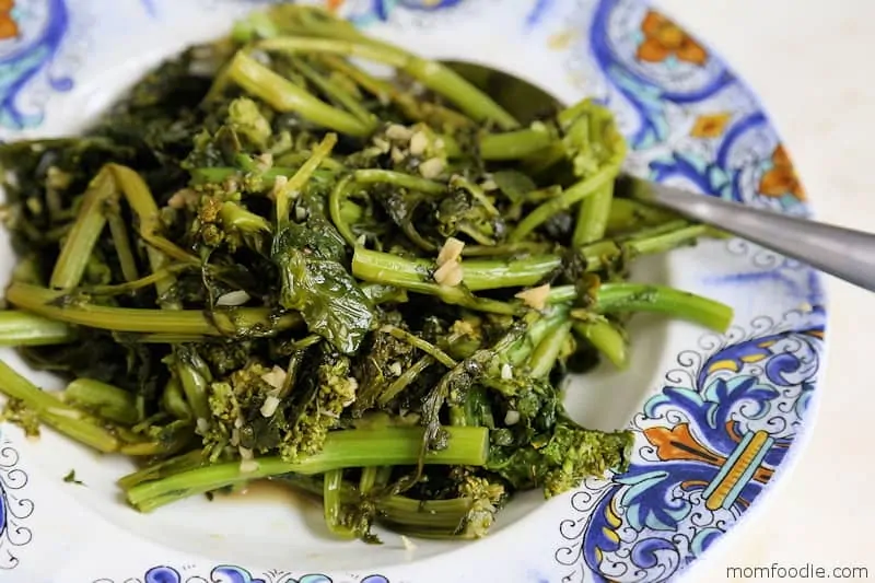 Broccoli Rabe on a blue and white porcelain dish with a spoon.