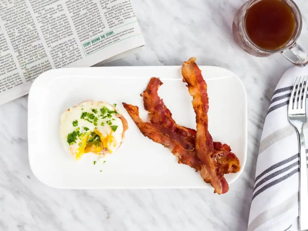 baked eggs florentine on a plate with bacon