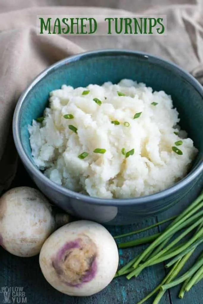 Mashed Turnips in a blue bowl next to raw turnips and chives.