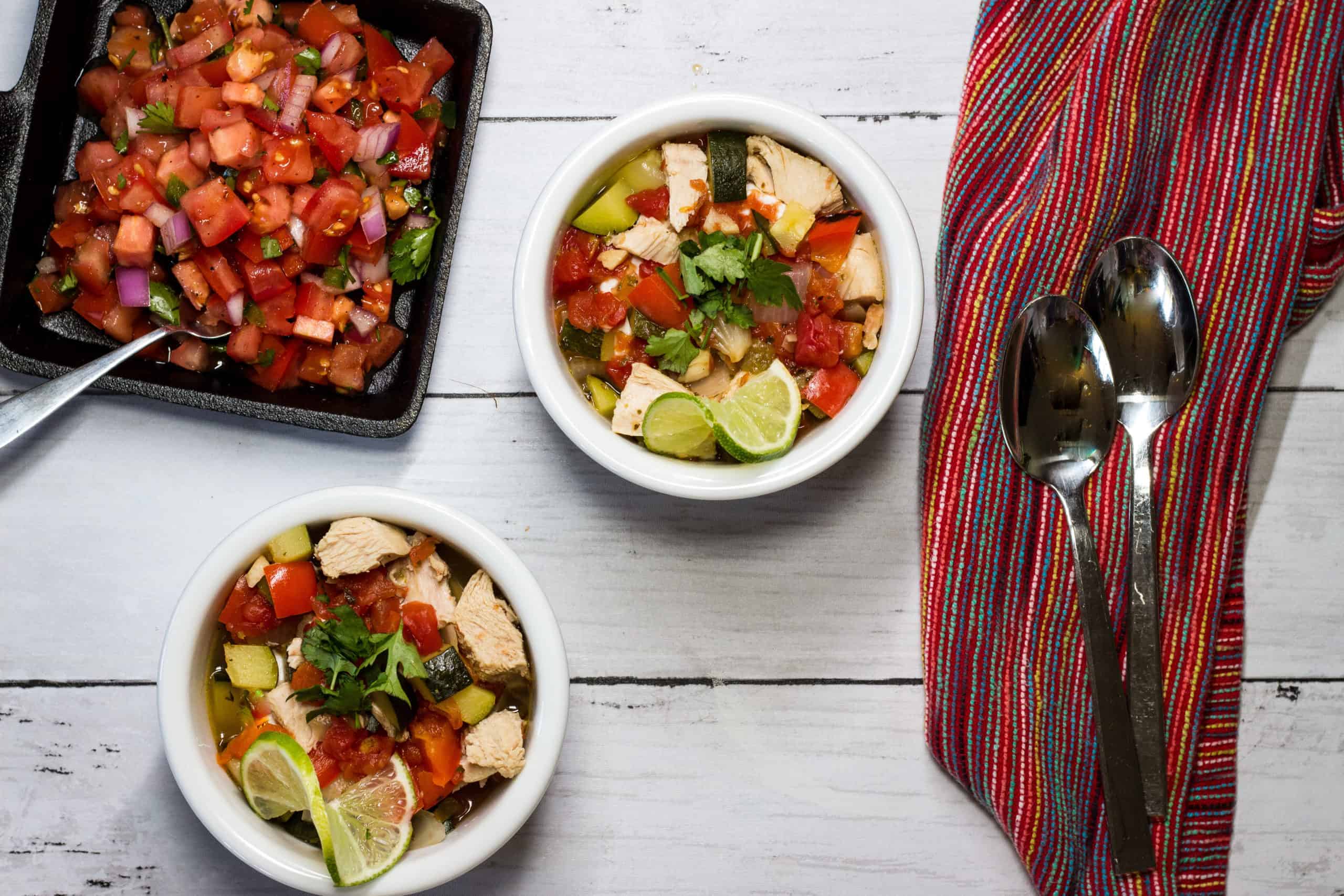 Two bowls of Mexican Turkey Soup with a side of salsa.