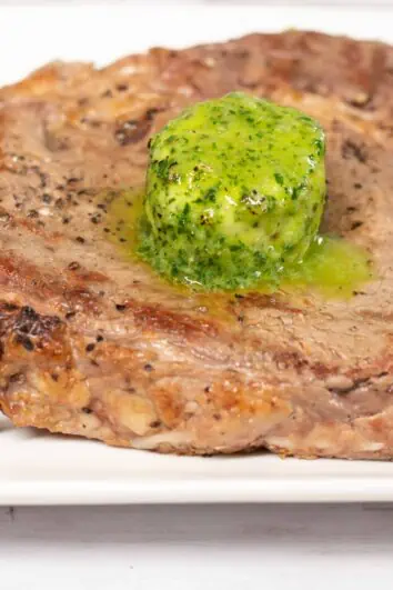 Thick and juicy ribeye steak topped with keto Garlic & Herb Butter Bomb.