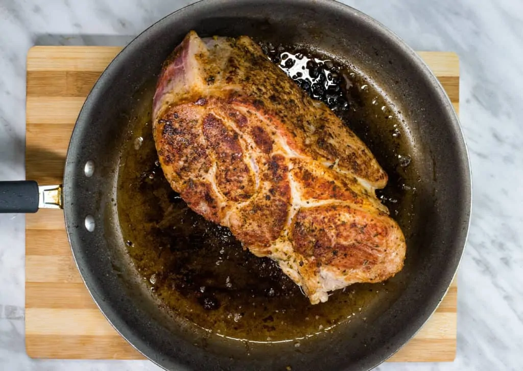 the rubbed pork shoulder is seared in a skillet